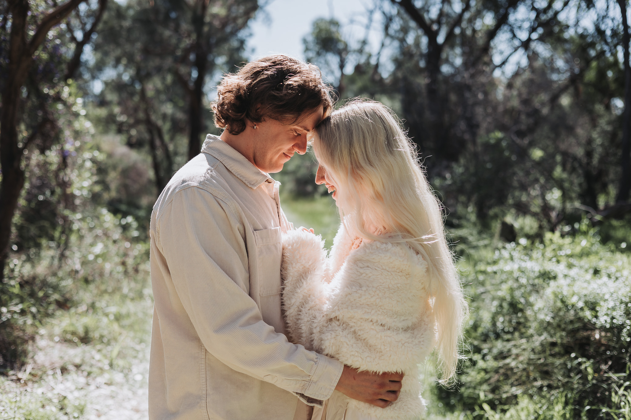 Couple touching foreheads on a sunlit forest path during a Perth couples photography session
