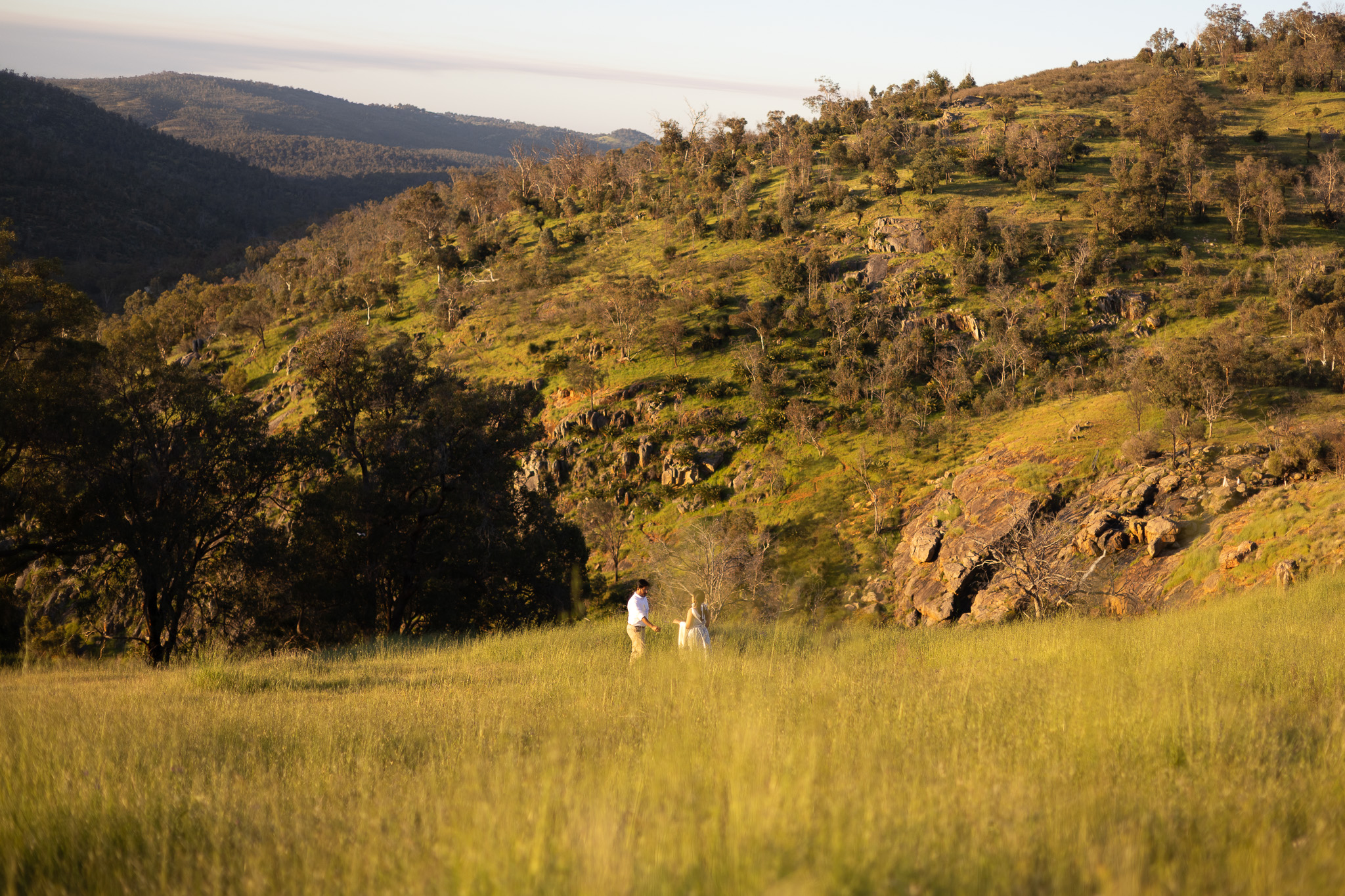Couple standing together in a sunlit grassy hillside landscape near Perth