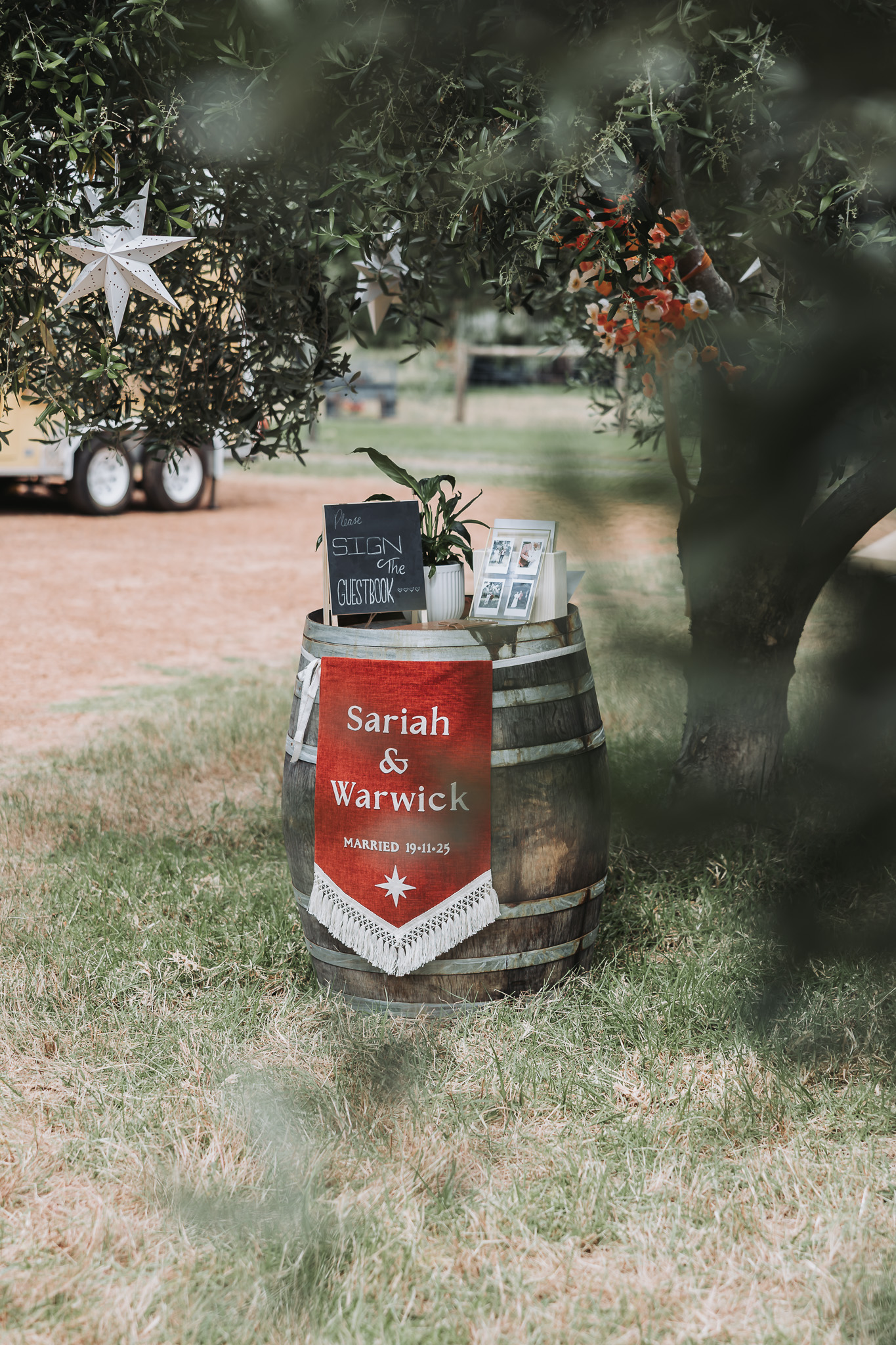 Outdoor wedding guestbook station on a wine barrel with a banner reading Sariah and Warwick married 19.11.23